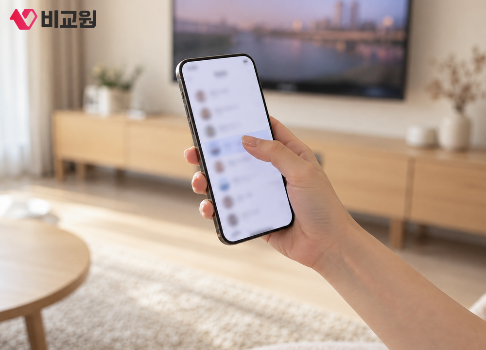TV 앞에서 휴대폰의 소리 출력 설정을 확인하는 손